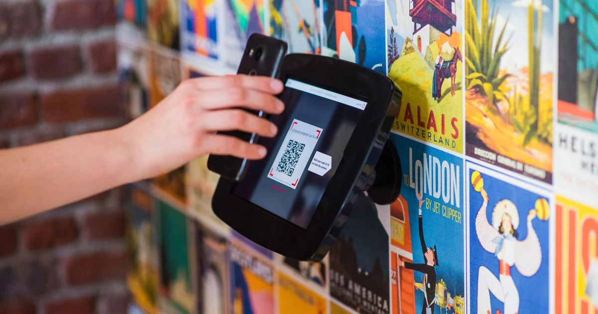 Manos sosteniendo un smartphone y escaneando un código QR