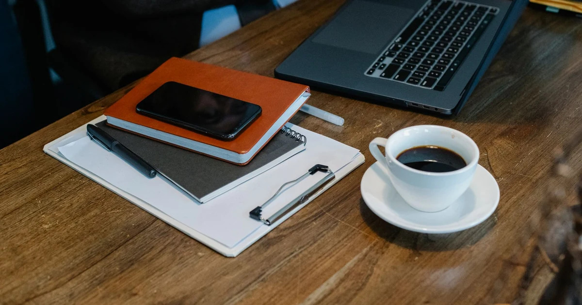 Mesa de trabajo con ordenador portátil, taza de café y teléfono inteligente