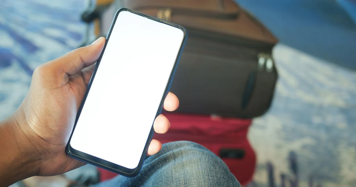 مسافر في صالة المطار يفحص هاتفه المحمول بتركيز