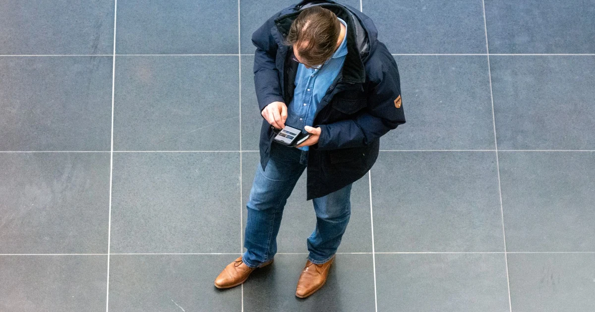 Viajante observando a tela do smartphone com ar de dúvida