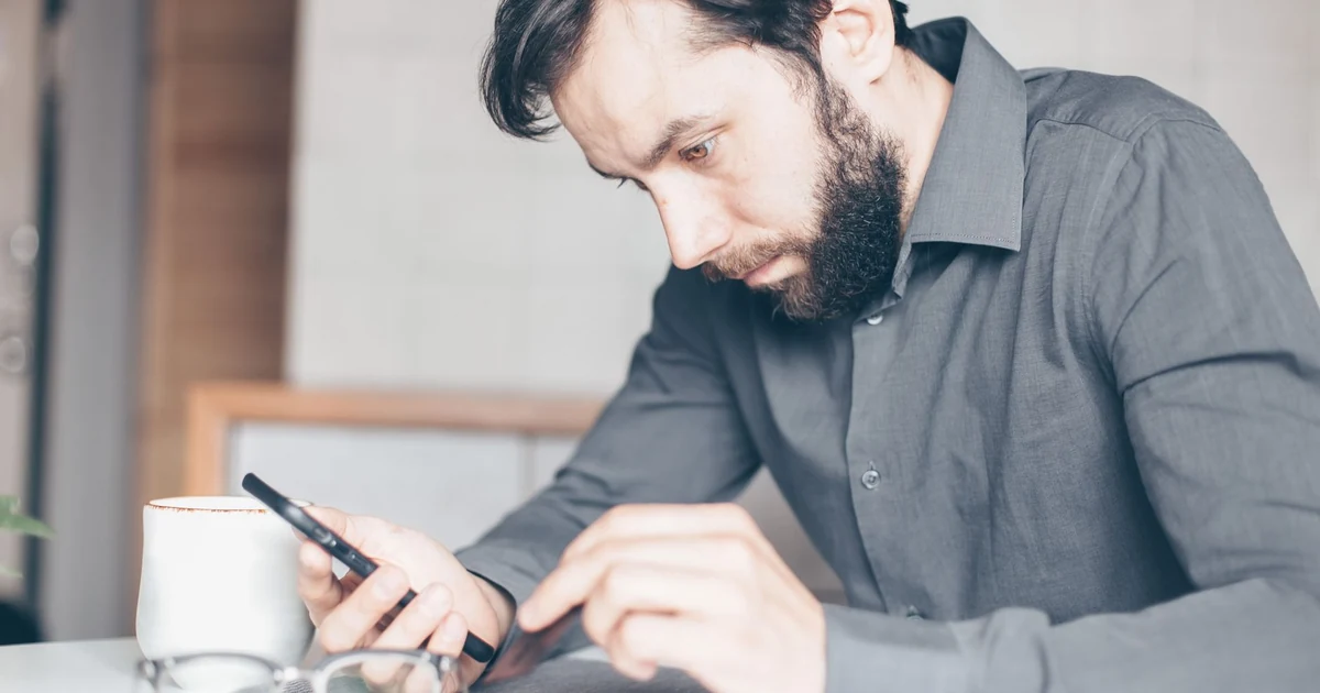 Persona mirando su teléfono móvil con gesto pensativo