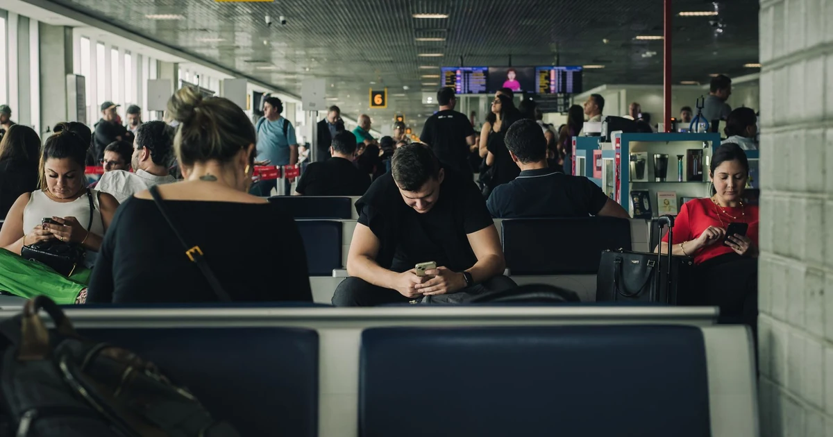 Voyageur à l'aéroport vérifiant son smartphone avec concentration