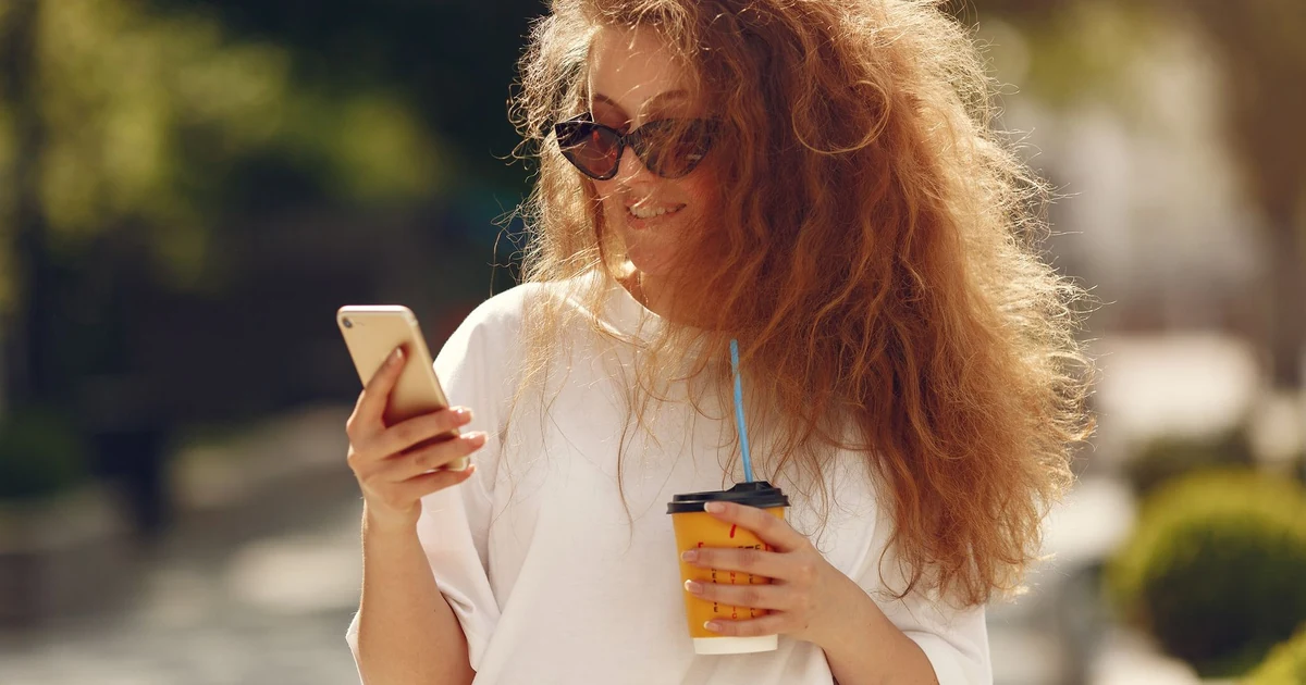 Turista in una piazza storica che scatta foto e consulta il telefono