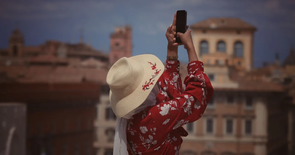 Turista tirando foto em praça histórica com smartphone