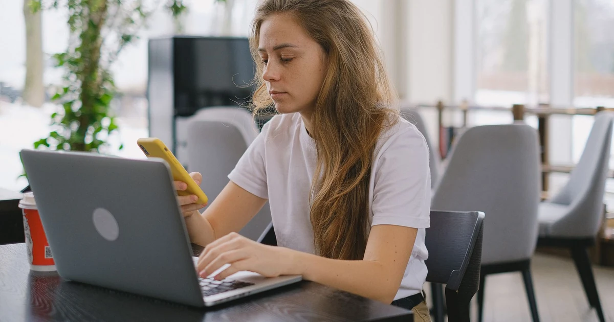 Pessoa trabalhando no notebook com café e smartphone na mesa